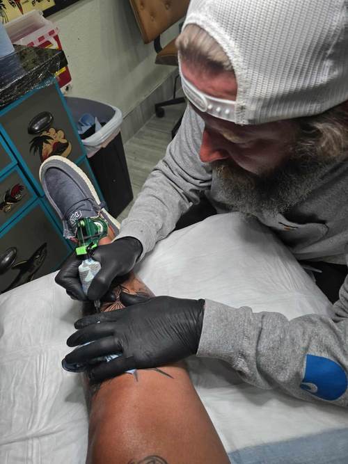 Jake tattooing a client at High Tide Tattoo