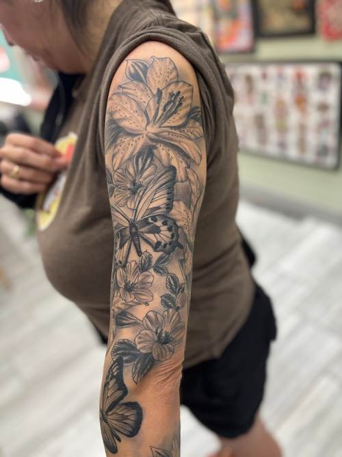 Black and grey floral sleeve tattoo with a butterfly