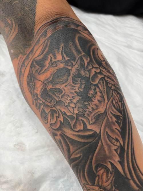 Black and grey skull tattoo on a forearm